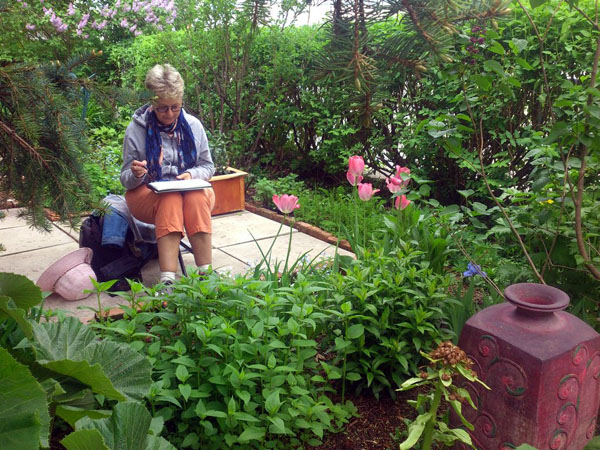 Claudette is in the zone, sketching a large vase and surrounding plants.